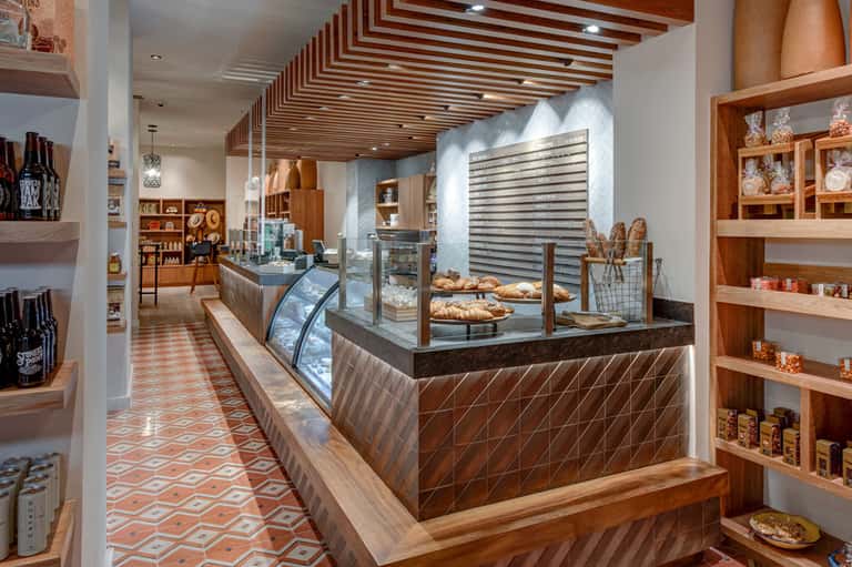 Modern bakery interior with wooden shelving, display cases, and geometric tile flooring