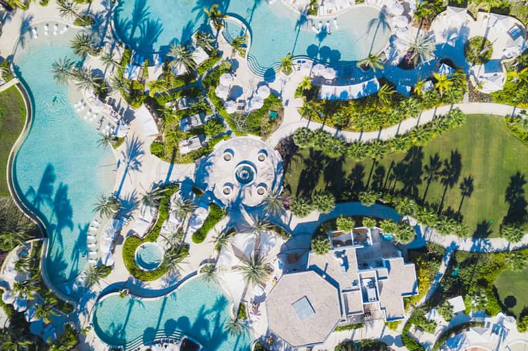 Aerial view of resort pools, palm trees, and manicured grounds
