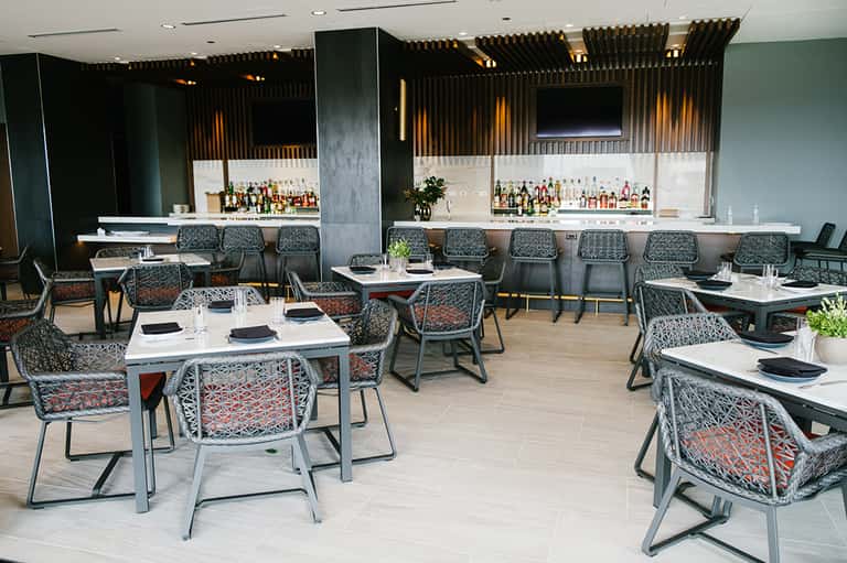Modern hotel restaurant and bar interior with patterned chairs and full bar setup