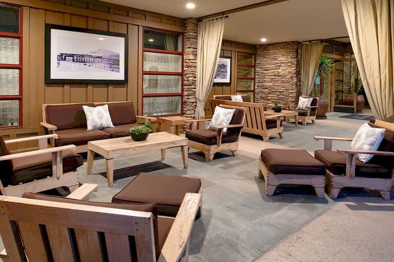 Modern hotel lobby lounge with wooden furnishings, stone accents, and brown upholstered seating