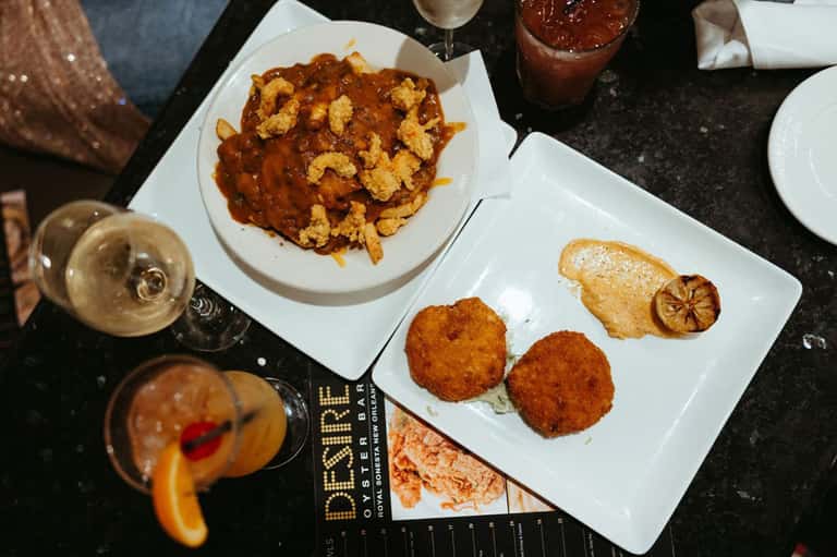 Gourmet dinner plates with fried calamari and seared fish beside cocktails in upscale restaurant setting