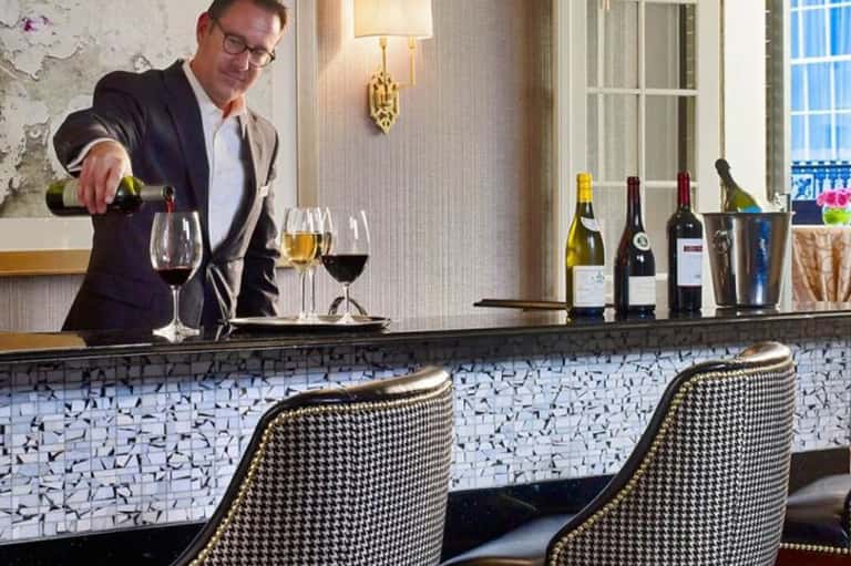 Bartender pouring wine at an upscale bar with houndstooth pattern and elegant interior design