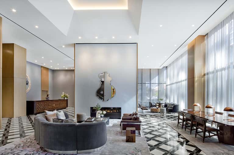 Luxury hotel lobby with curved sofa, fireplace, high ceilings, and modern décor