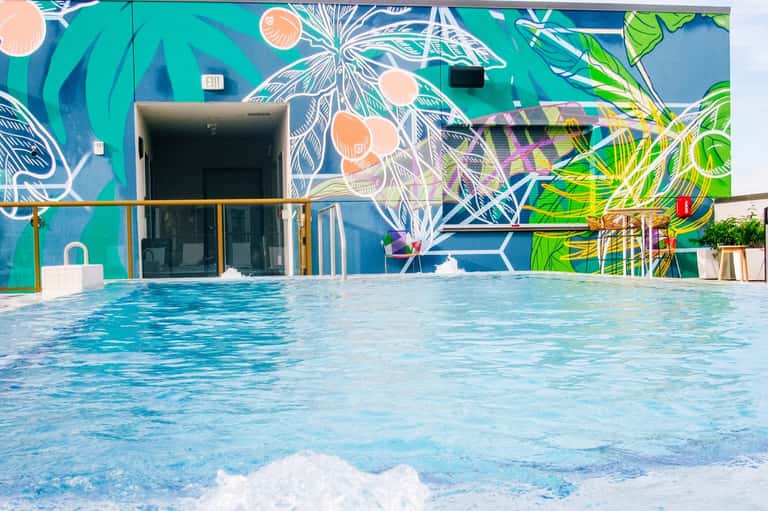 Resort pool with vibrant turquoise water and colorful floral mural on modern building facade