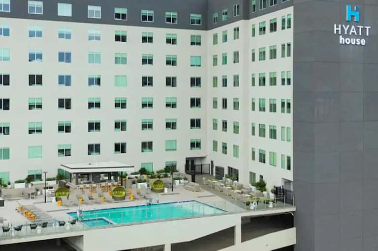 Aerial view of courtyard pool surrounded by Hyatt house building with yellow umbrellas and modern architecture
