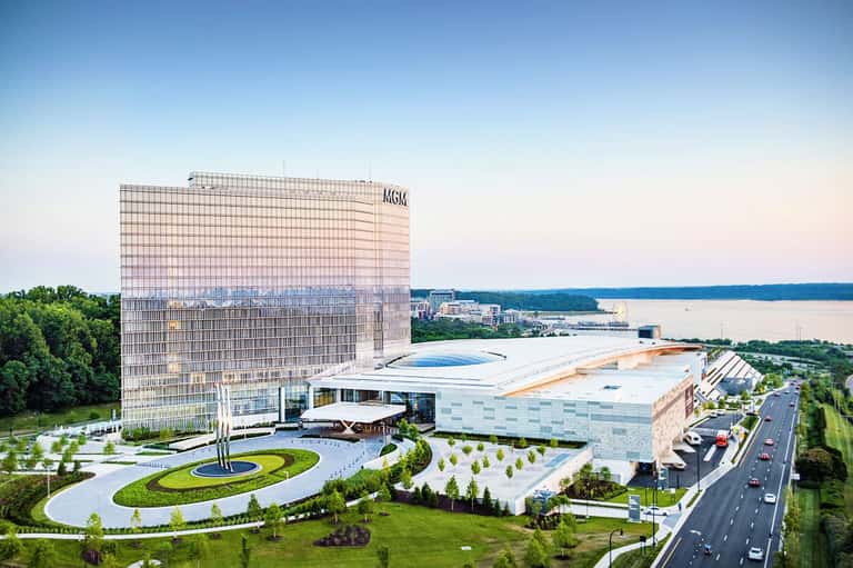 Modern MGM hotel tower overlooking a lake with manicured grounds and curved white building extension