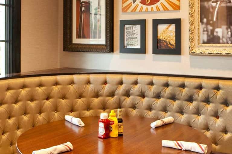 Fine dining restaurant with tufted gold booth seating, framed artwork, and place settings