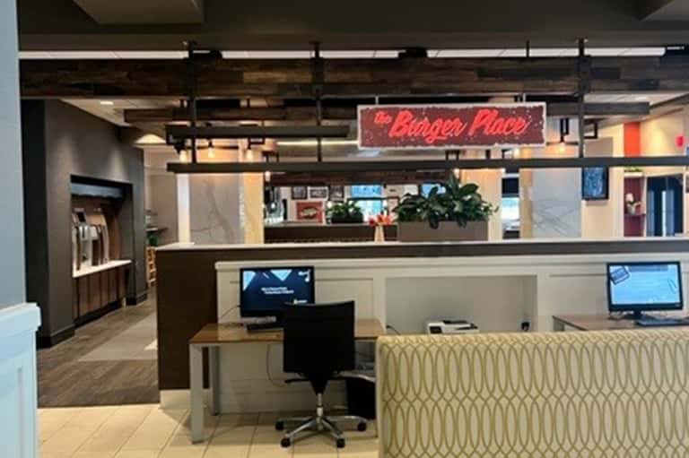 Hotel reception desk with neon sign, check-in counter, plants, and modern lobby design