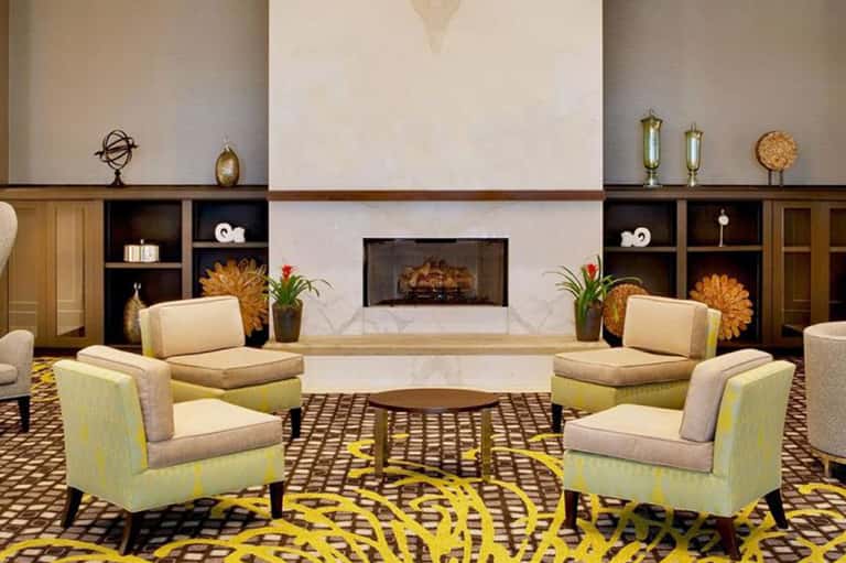Elegant hotel lobby lounge with fireplace, modern chairs, and decorative gold accents