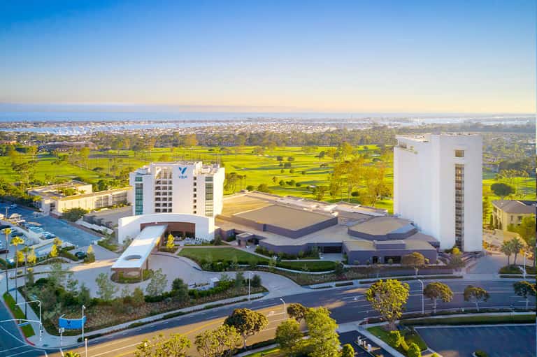 Modern resort complex with twin towers overlooking green landscape and bay