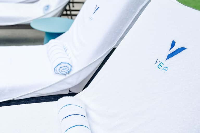 Close-up of folded white towels with blue spa resort logo embroidered on them