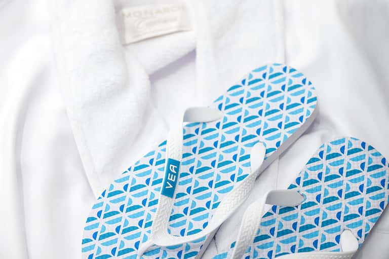 White bathroom slippers with blue geometric pattern on fluffy white towel