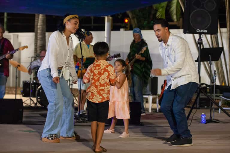 Live beach concert with performers entertaining families under covered outdoor pavilion