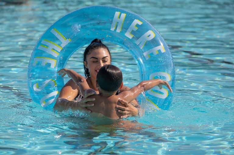 Woman and child playing in resort pool with inflatable blue ring