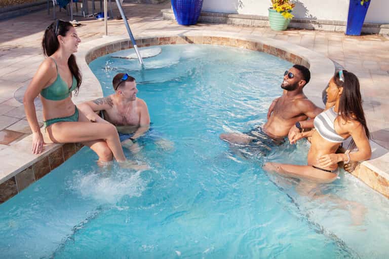 Four guests relaxing in hot tub spa with tropical surroundings