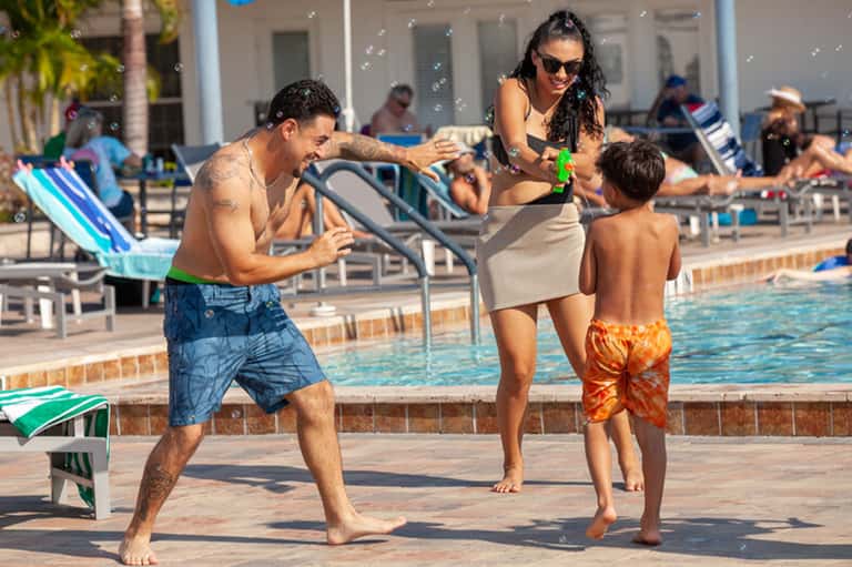 Family enjoying activity at resort pool deck with parents and children playing together