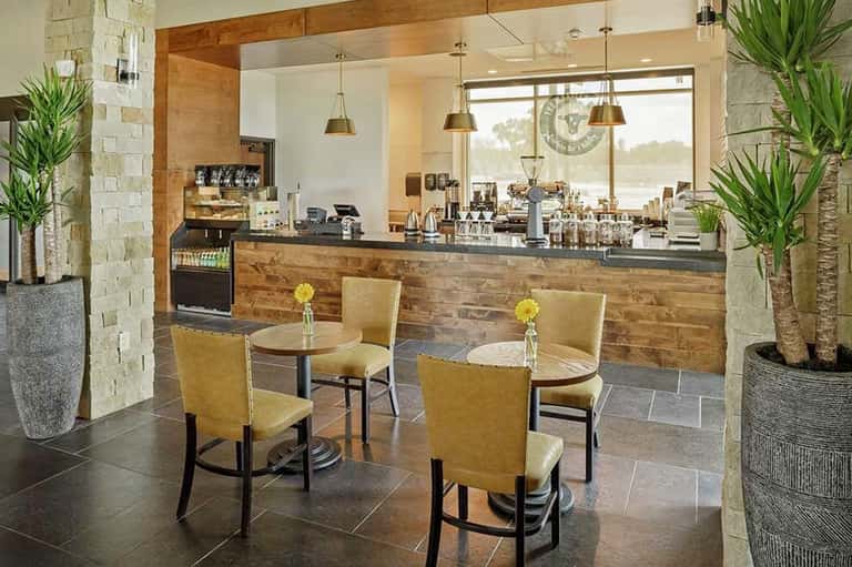 Modern hotel café counter with wood accents, pendant lighting, and ocean view through large windows