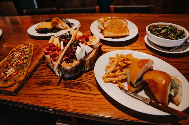 Fine dining table with charcuterie board, burgers, and side dishes