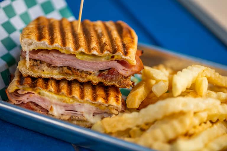 Grilled ham and cheese sandwich with crispy golden bread served with french fries on blue plate