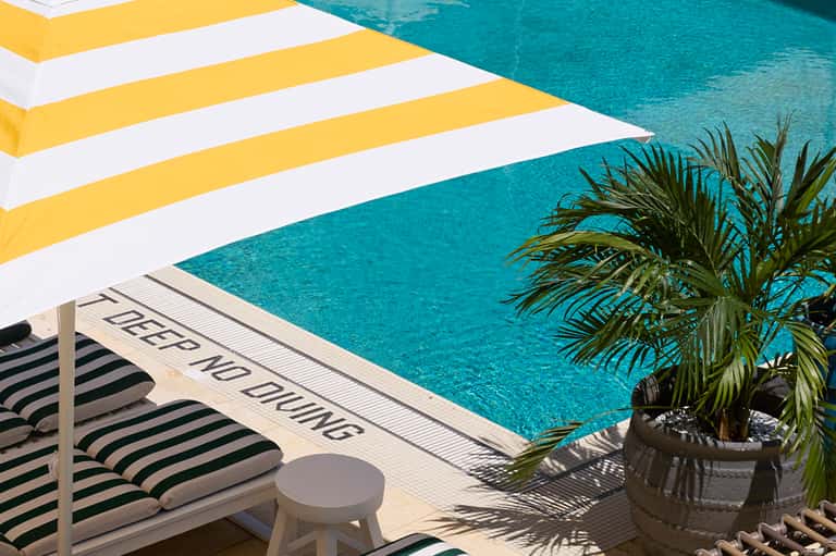 Poolside detail with yellow and white striped umbrella and 'Deep No Diving' sign