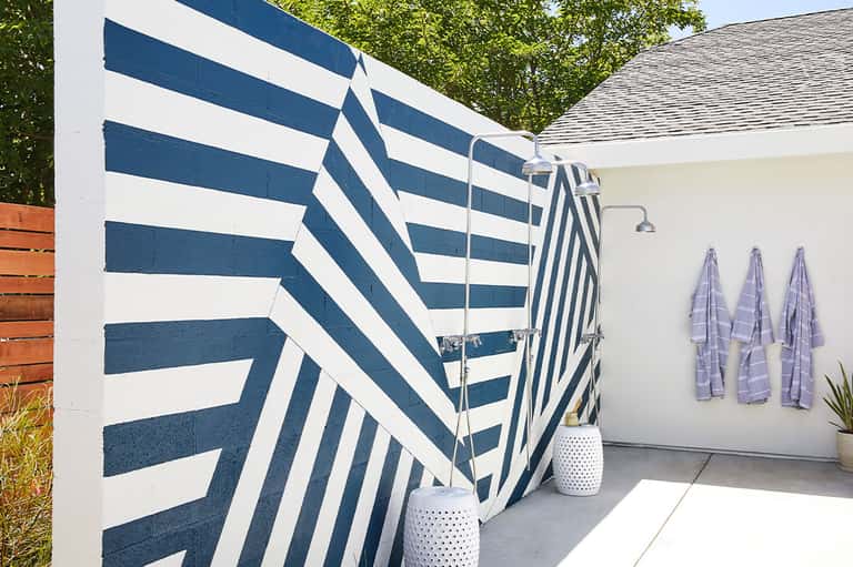 Outdoor shower area with navy striped privacy screens and towels