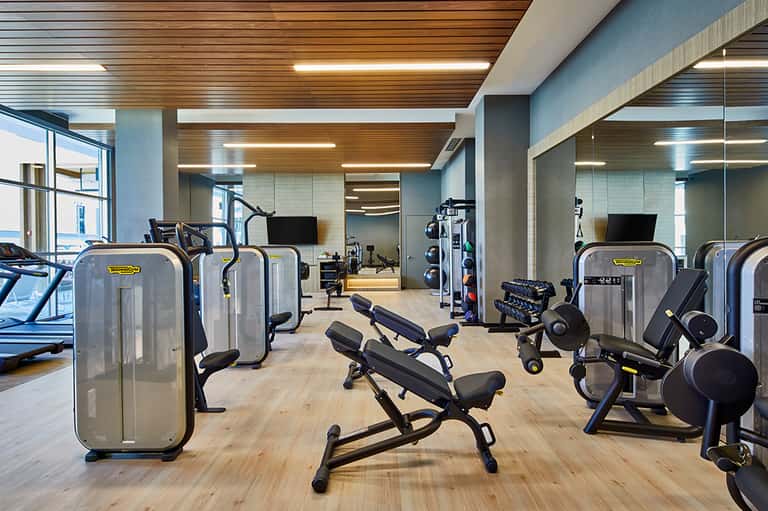 Modern fitness center with exercise equipment, wooden ceiling, and large windows