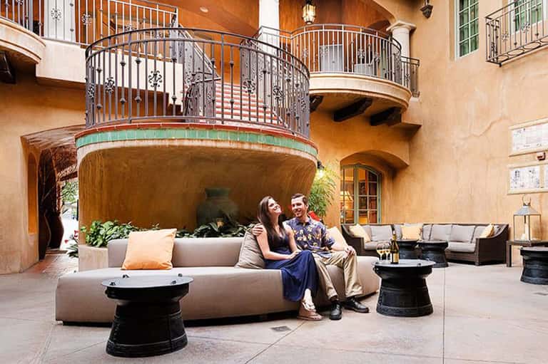 Courtyard lounge with curved seating, curved balcony railings, and warm stucco walls