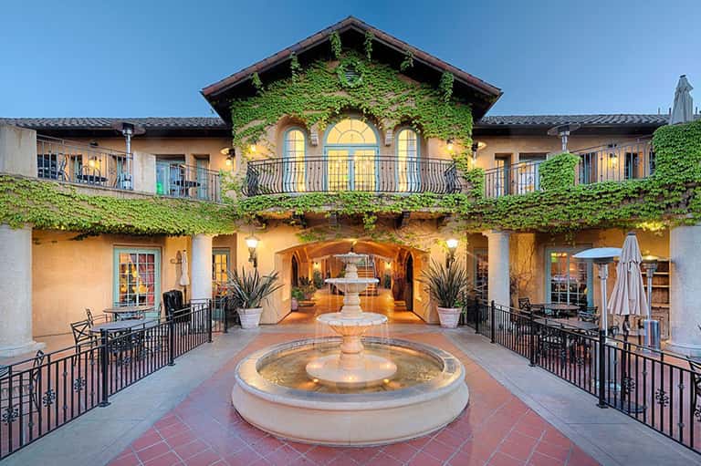 Spanish colonial courtyard with ivy-covered walls, central fountain, and arched passageways