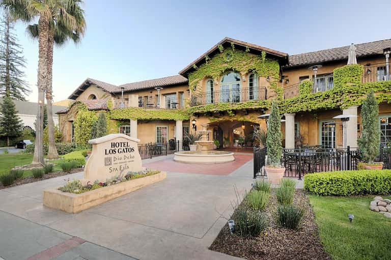 Spanish colonial hotel entrance with ivy-covered façade and manicured landscaping