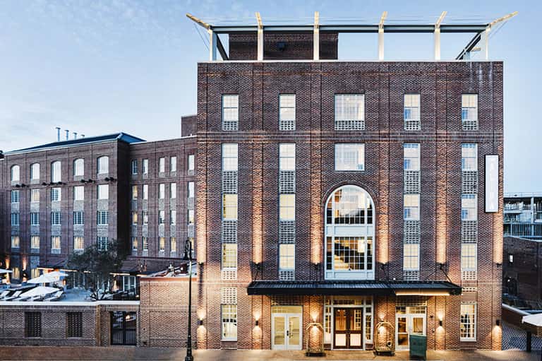 Historic brick building facade with illuminated arched entrance and contemporary rooftop structure