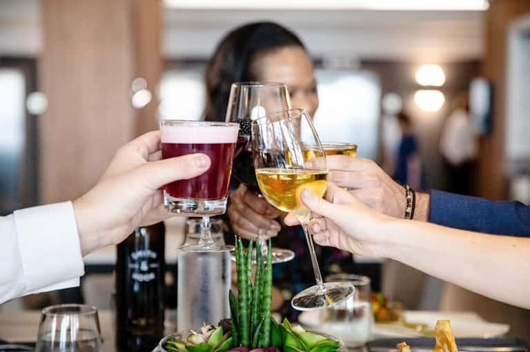 People toasting with cocktails and wine glasses at an indoor event or celebration