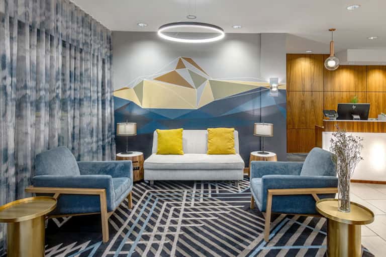 Modern hotel lobby with geometric art wall, contemporary furnishings, and wood accents