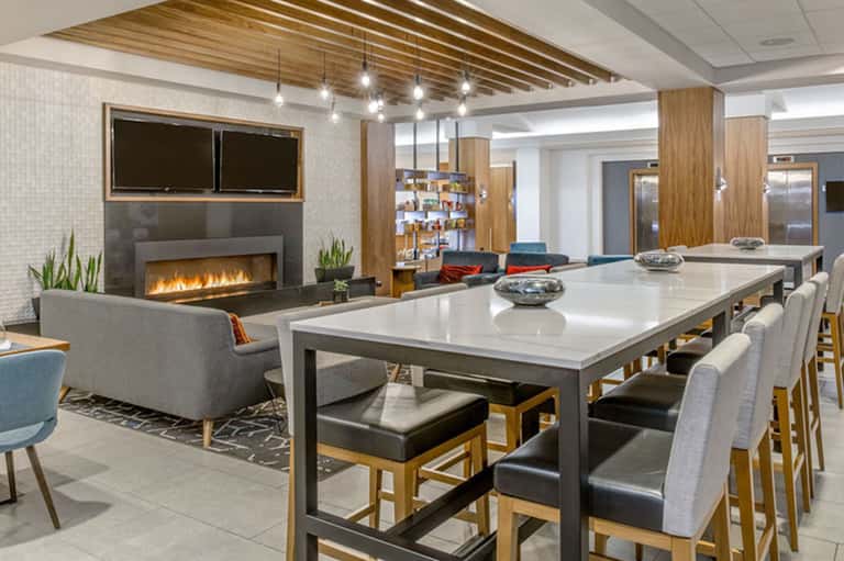 Modern resort common area with fireplace, dining table, wood ceiling, and contemporary furnishings