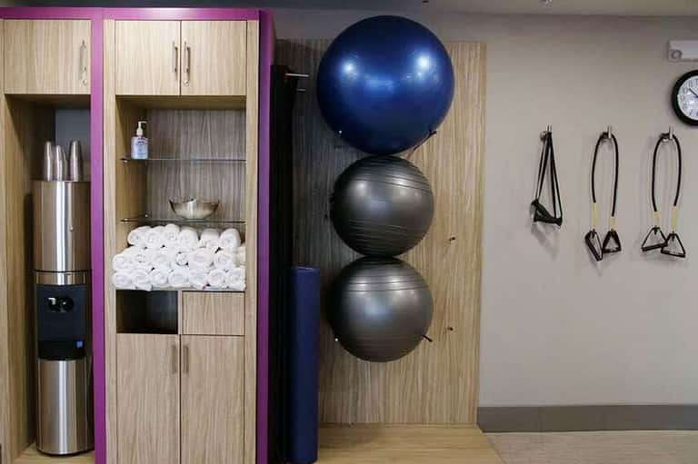 Fitness center with exercise balls stacked vertically, storage cabinets, water dispenser, and equipment
