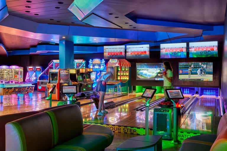 Neon-lit arcade and bowling alley with colorful games and luminous ceiling