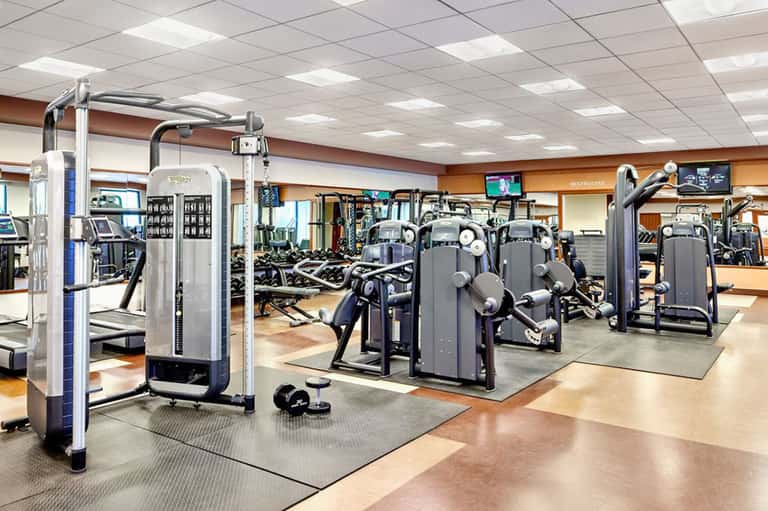Fitness center with cardio equipment and weight machines under bright ceiling lights