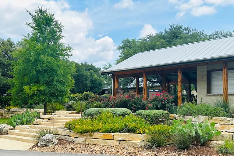 Modern ranch-style building with metal roof, wooden posts, and xeriscape landscaping with succulents