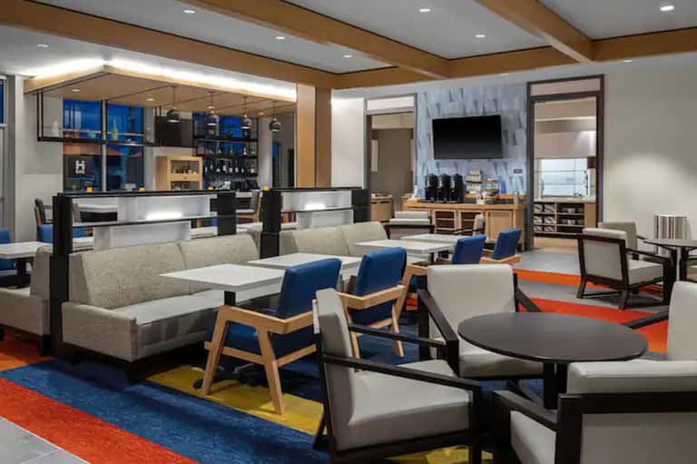 Modern resort lobby lounge with contemporary seating, bar area, and colorful geometric floor pattern
