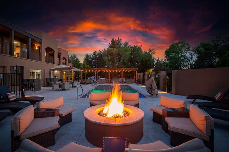 Luxury resort courtyard with fire pit, lounge seating, and glowing pool at dusk
