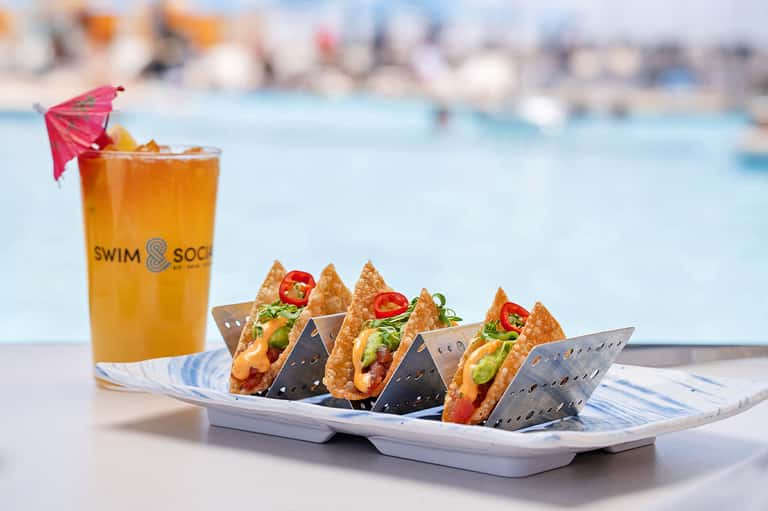 Gourmet tacos and tropical drink by pool at beach resort restaurant