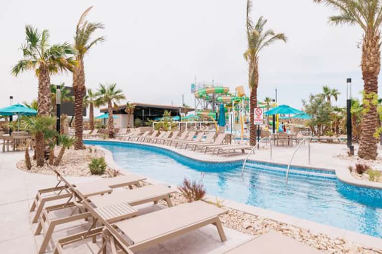 Resort lazy river with palm trees, water slides, and lounge chairs