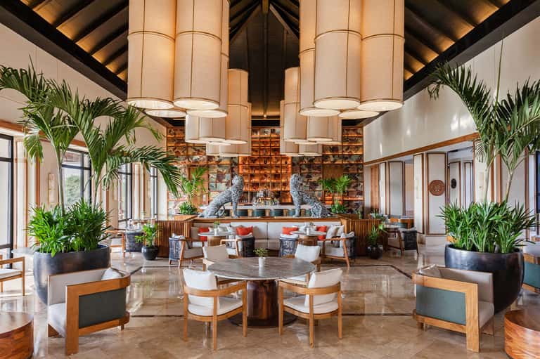 Spacious resort lobby with soaring ceilings, decorative birds, plants, and lounge seating