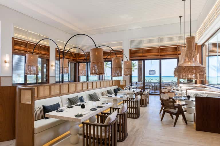 Upscale beachfront restaurant with woven pendant lights, built-in seating, and ocean views