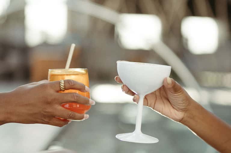 Hands holding tropical cocktails clinking together at resort gathering
