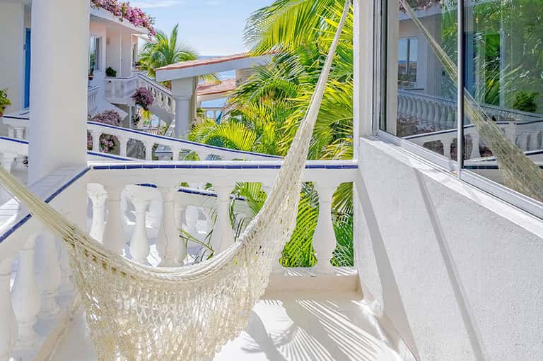 Coastal balcony with hammock, ocean views, and tropical palm vegetation