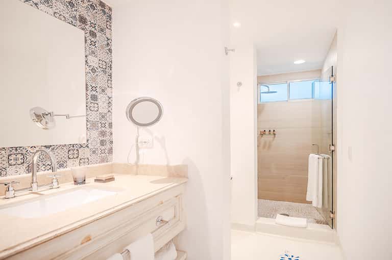 Luxury bathroom with marble vanity, decorative tile backsplash, and walk-in shower with ocean view