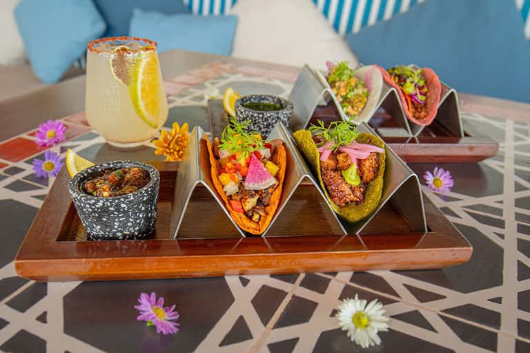 Colorful taco platter with cocktails and decorative flowers on geometric table setting