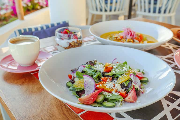 Colorful salad dish with coffee and other plates on outdoor patio