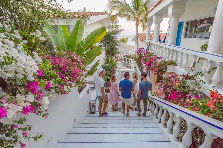 Family walking through resort corridor lined with vibrant pink and white flowering bougainvillea