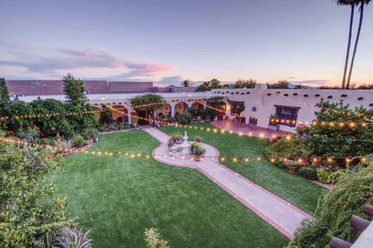 Waterfront garden terrace with illuminated archways, manicured lawn, and water views at twilight